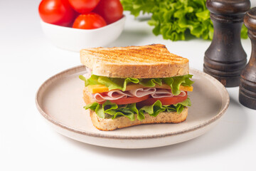 Close-up of two sandwiches with bacon, salami, prosciutto and fresh vegetables on rustic wooden cutting board. Club sandwich concept - 750911103