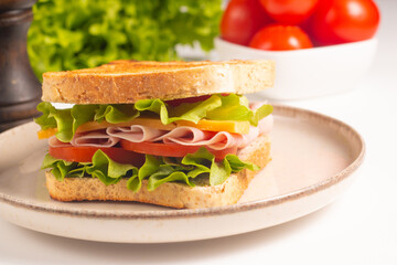 Close-up of two sandwiches with bacon, salami, prosciutto and fresh vegetables on rustic wooden cutting board. Club sandwich concept - 750911158