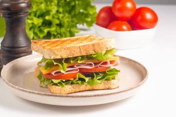 Close-up of two sandwiches with bacon, salami, prosciutto and fresh vegetables on rustic wooden cutting board. Club sandwich concept - 750911181