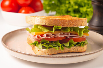 Close-up of two sandwiches with bacon, salami, prosciutto and fresh vegetables on rustic wooden cutting board. Club sandwich concept - 750911187