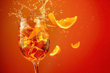 An Aperol Spritz cocktail with splashes, on an orange background with copy space for text