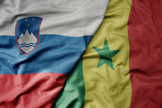 big waving national colorful flag of senegal and national flag of slovenia.