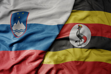 Fototapeta premium big waving national colorful flag of uganda and national flag of slovenia.
