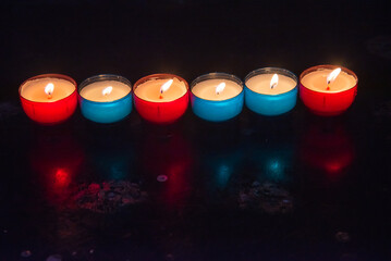 Burning candles in the church. Raw of colorful red blue burning candles in dark. Religious holiday celebration background.  Hope, pray concepts.