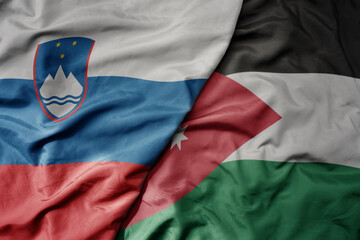 big waving national colorful flag of jordan and national flag of slovenia.