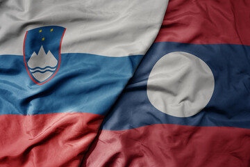 big waving national colorful flag of laos and national flag of slovenia.