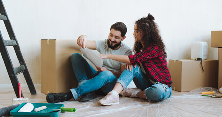 Caucasian young and cheerful man and woman talking and deciding how to decorate a room and colour...