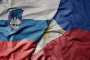 Fototapeta premium big waving national colorful flag of philippines and national flag of slovenia.