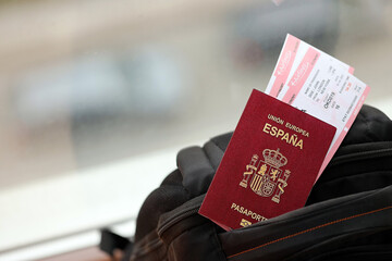 Red Spanish passport of European Union with airline tickets on touristic backpack close up. Tourism and travel concept
