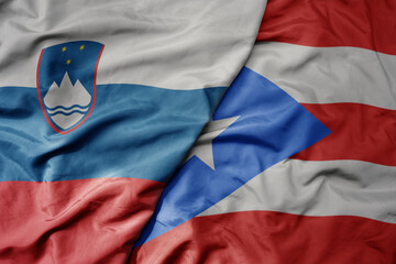 big waving national colorful flag of puerto rico and national flag of slovenia.
