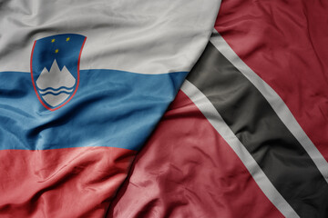 big waving national colorful flag of trinidad and tobago and national flag of slovenia.