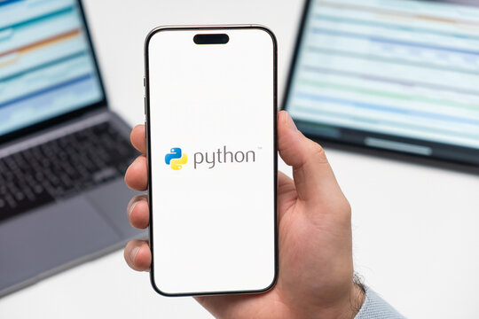 PRAGUE, CZECH REPUBLIC - JANUARY 21 2024: Python logo on the screen of smartphone in mans hand on the workplace background. 
