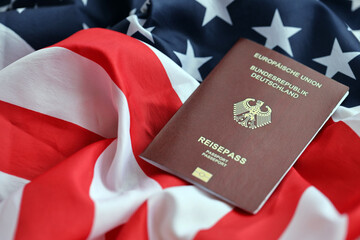 Red German passport of European Union on United States national flag background close up. Tourism and diplomacy concept