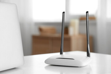 Modern wi-fi router on white table in living room, closeup