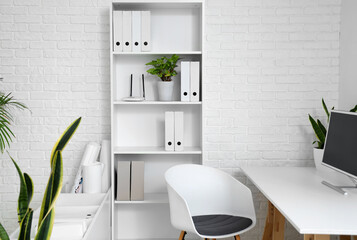 Shelf unit with wi-fi router, plant and folders in office - obrazy, fototapety, plakaty