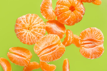 Flying sweet peeled mandarins on green background