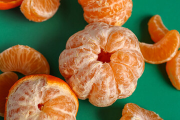 Sweet peeled mandarins on green background