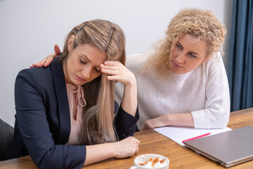 In a moment of vulnerability, a woman holds her head in despair across from an empathetic listener, capturing the challenge of facing bankruptcy and the crucial role of therapeutic conversation.