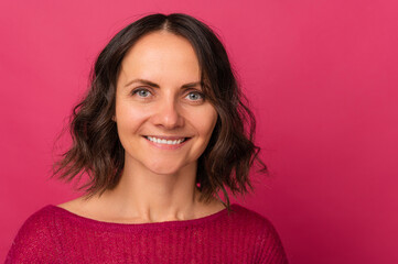 Close up studio portrait of a beautiful smiling middle age woman over pink backdrop.