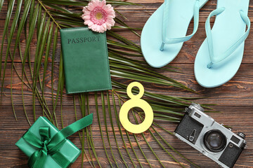 Composition with paper figure 8, passport, flip-flops and palm leaf on wooden background....