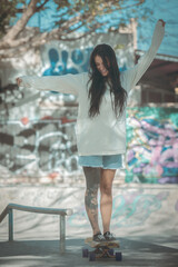 Skate park lifestyle image of a tattoo girl on skateboard