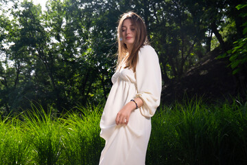 A young girl in a white dress poses on a summer terrace. Weekend in the big city