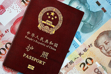 Red passport of People Republic of China and chinese yuan money bills. PRC chinese passport on bright background close up