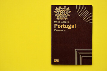 Red Portugal passport of European Union on yellow background close up. Tourism and citizenship concept