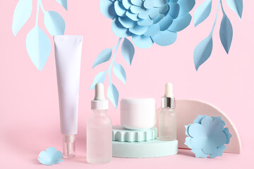 Facial cosmetic products composition with paper flowers on pink background