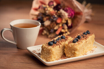 A cozy tea time scene with lemon, honey, cake, and blueberries on a wooden table