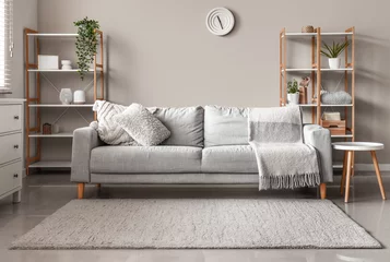 Fototapeten Interior of modern living room with  sofa, table and wooden racks near white wall © Pixel-Shot