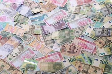 Many banknotes of different currency. Background of big amount of random money bills close up