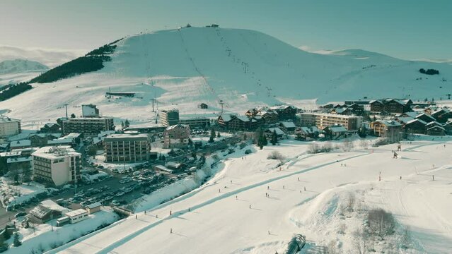 Aerial drone shot of Alpine ski track and hotels in Alpe d'Huez ski resort. France