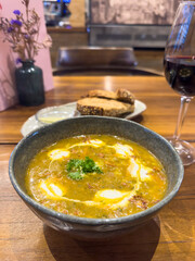 Traditional Persian barley soup with carrot and parsley on the table in a lunch cafe, offering a tantalizing glimpse of culinary heritage amidst the cosy ambience, with a view of the serving counter.