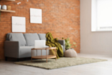 Loft style living room with comfortable sofa and table, blurred view