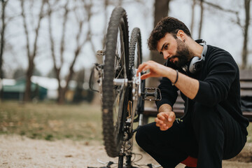 Focused entrepreneur taking time off to fix and maintain his mountain bike outdoors in a tranquil...