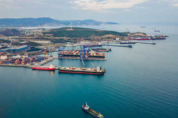 Cargo vessels uploading at freight cargo port terminal. Aerial view