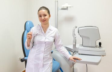 Ophthalmologist stands in room, holding glasses with smile