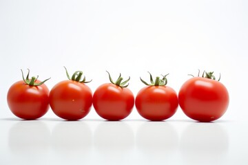 A row of five red tomatoes are lined up on a white background