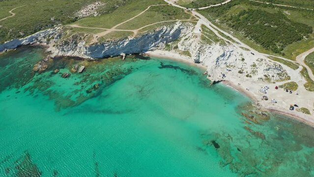 Alacati Halk beach. Turquoise sea and rocky beach. Bird eye view of Delikli Koy beach in Alachati, Turkiye. Drone approaching the beach