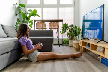 A smiling teenage girl playing a console game in the living room of her home