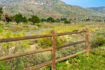 Fototapeta na wymiar A wooden corral fence with a landscape of Irvine Regional Park in Orange County, California