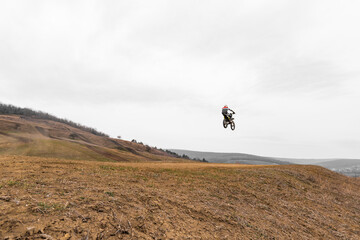 Person soaring on dirt bike in the sky over grassy field