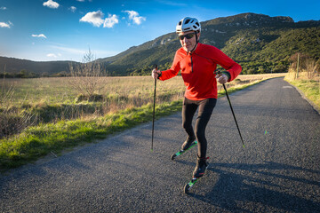 un homme âgé sur des ski-roues en plaine campagne  sur une route goudronnée - 750966139