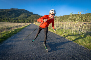 un skieur sur des ski-roues en pleine campagne  sur une route goudronnée