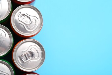 Energy drink in cans on light blue background, top view. Space for text