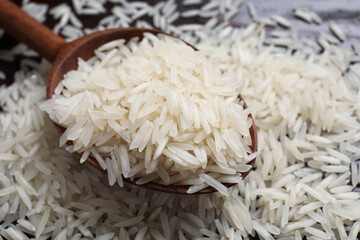 Raw basmati rice and wooden spoon on table, closeup