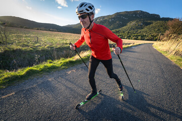 un homme fait du ski-roues sur une route goudronnée - obrazy, fototapety, plakaty