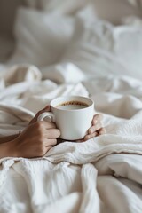 A person holding a cup of coffee on a cozy bed. Ideal for lifestyle and relaxation concepts