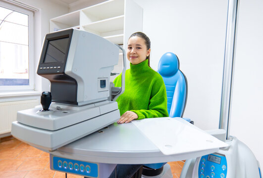 Woman in green sweater using computer at table with monitor - Powered by Adobe
